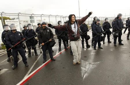 A protester gestures in front of a line of police officers in riot gear during the Occupy movement's attempts to shut down West Coast ports in Oakland, California December 12, 2011. REUTERS/Robert Galbraith