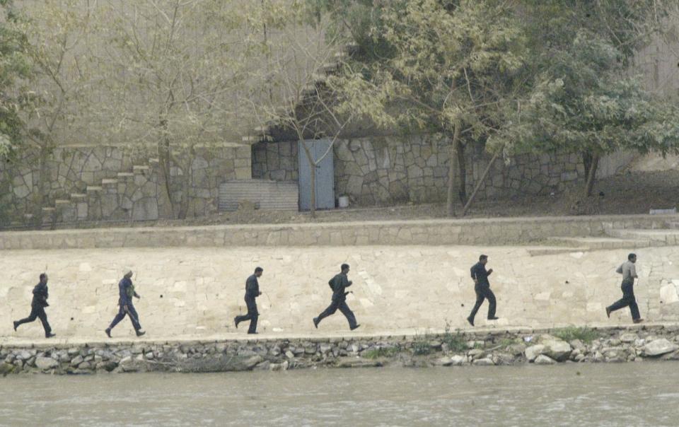 FILE - Iraqi soldiers are seen running away on the banks of the Tigris river as U.S. tanks roll into Baghdad, outside Saddam Hussein's presidential palace April 7, 2003. Coalition soldiers took over key buildings, as gunfire and explosions thundered in many parts of the battered Iraqi capital. (AP Photo/Jerome Delay)