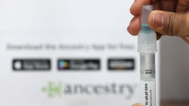 A vial of spit in front of the AncestryDNA logo