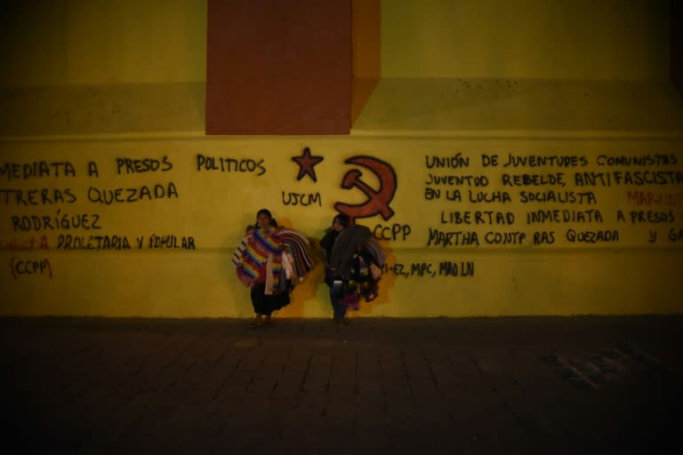 Two indigenous women stand near graffiti on February 11, 2016 at the San Cristobal de Las Casas cathedral in Chiapas state where Pope Francis will visit