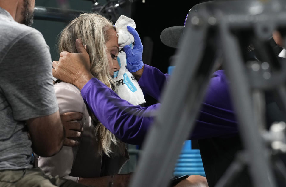 Colorado Rockies television reporter Kelsey Wingert is attended to after being hit by a foul ball off the bat of San Francisco Giants' Austin Slater in the ninth inning of a baseball game Monday, May 16, 2022, in Denver. The announcer, who was seated in the first-base camera well, was taken from the game after being struck in the head by the ball. (AP Photo/David Zalubowski)