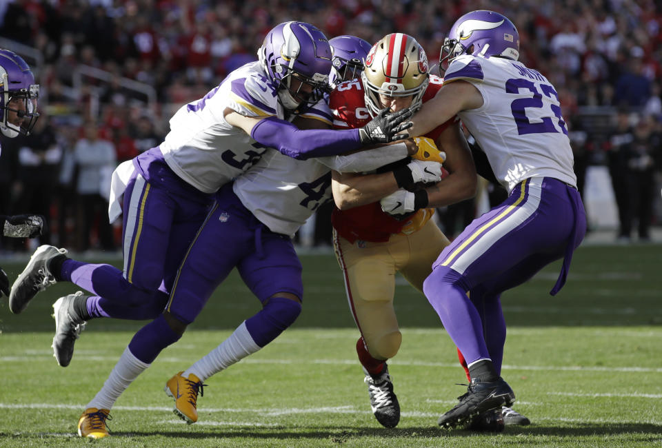 San Francisco 49ers tight end George Kittle, center, is tackled by Minnesota Vikings Minnesota Vikings free safety Harrison Smith, right, and other defenders during the first half of an NFL divisional playoff football game, Saturday, Jan. 11, 2020, in Santa Clara, Calif. (AP Photo/Marcio Jose Sanchez)