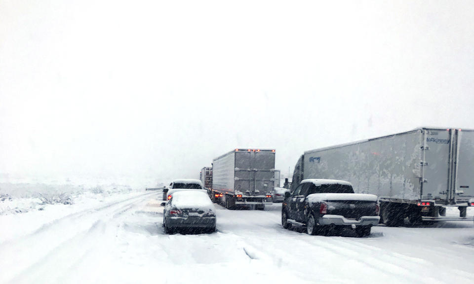 This photo provided by Johnny Lim shows a snow covered northbound I-15 in the Cajon Pass between the San Bernardino Mountains and the San Gabriel Mountains in Southern California on Thursday, Dec. 26, 2019. Lim, of Corona, said he's been stuck in his vehicle for about five hours on his way to Las Vegas. A powerful winter storm brought a deluge of rain and snow to Southern California, triggering tornado warnings and bringing post-Christmas travel to a halt on major routes. (Johnny Lim via AP)