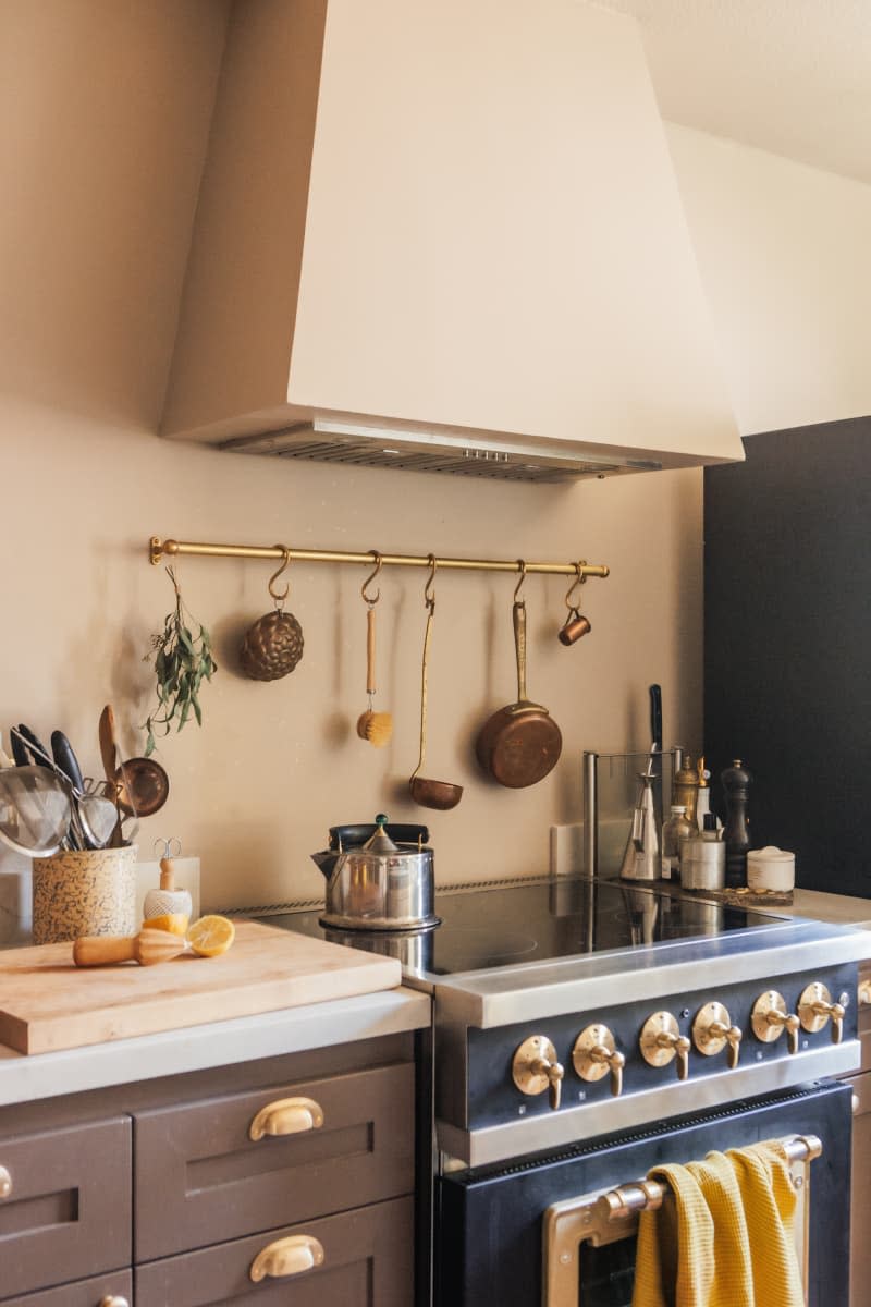 beige kitchen with taupe drawers and bar with pans and utensils hanging over stove