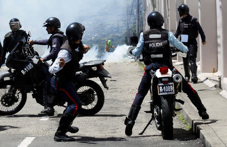 A riot police officer throws a stone during clashes with opposition supporters in a rally to demand a referendum to remove President Nicolas Maduro in San Cristobal, Venezuela October 24, 2016. REUTERS/Carlos Eduardo Ramirez