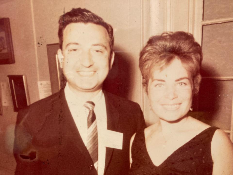 A black and white image of a couple wearing a shirt and tie and a dark, sleeveless dress.