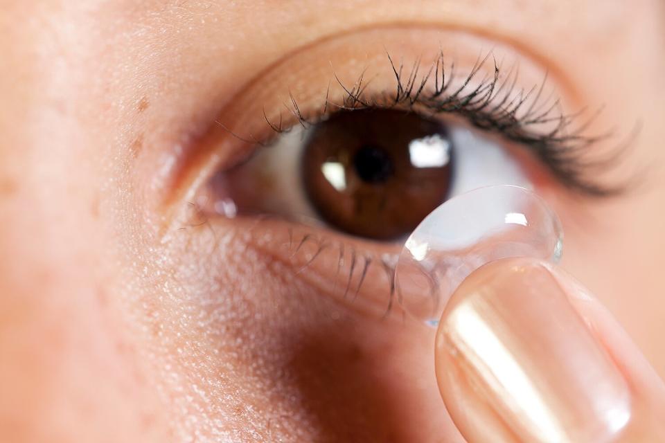 Macro shot with selective focus on the contact lens as a wearer inserts one into their eye.