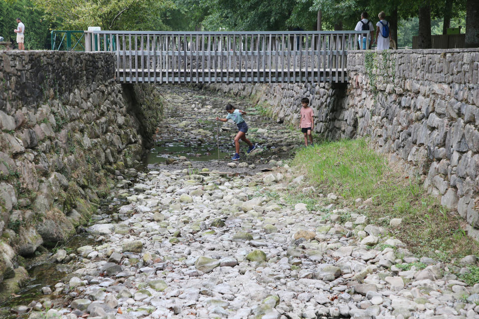 Dos niños juegan en el lecho reseco del río Galardi en Ascain (Francia) el 12 de julio del 2022. (AP Photo/Bob Edme)