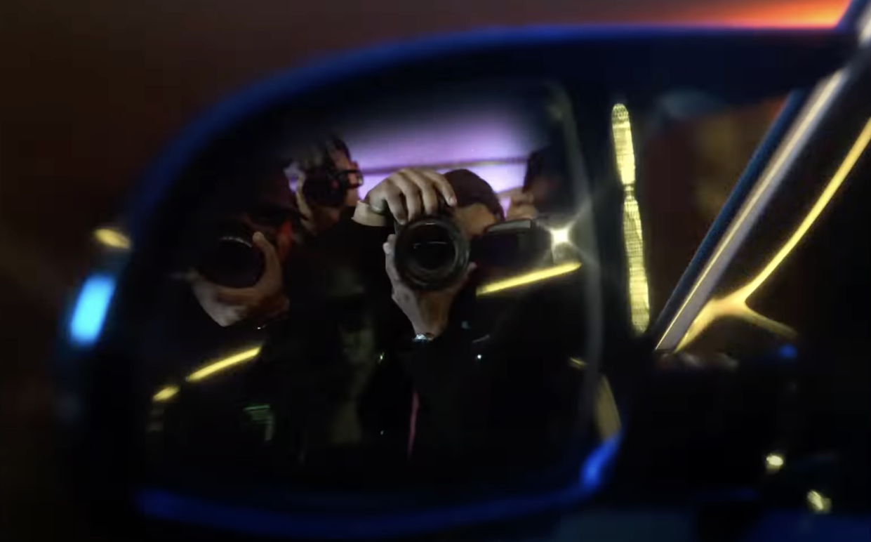 Photographers are shown in a car mirror in this still from the BMW XM promo video.