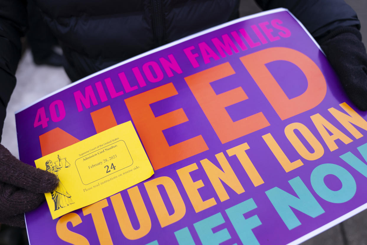 A person shows their ticket to attend the Supreme Court oral arguments about student debt relief. Below the ticket is a sign reading: 40 million families need student loan relief now.