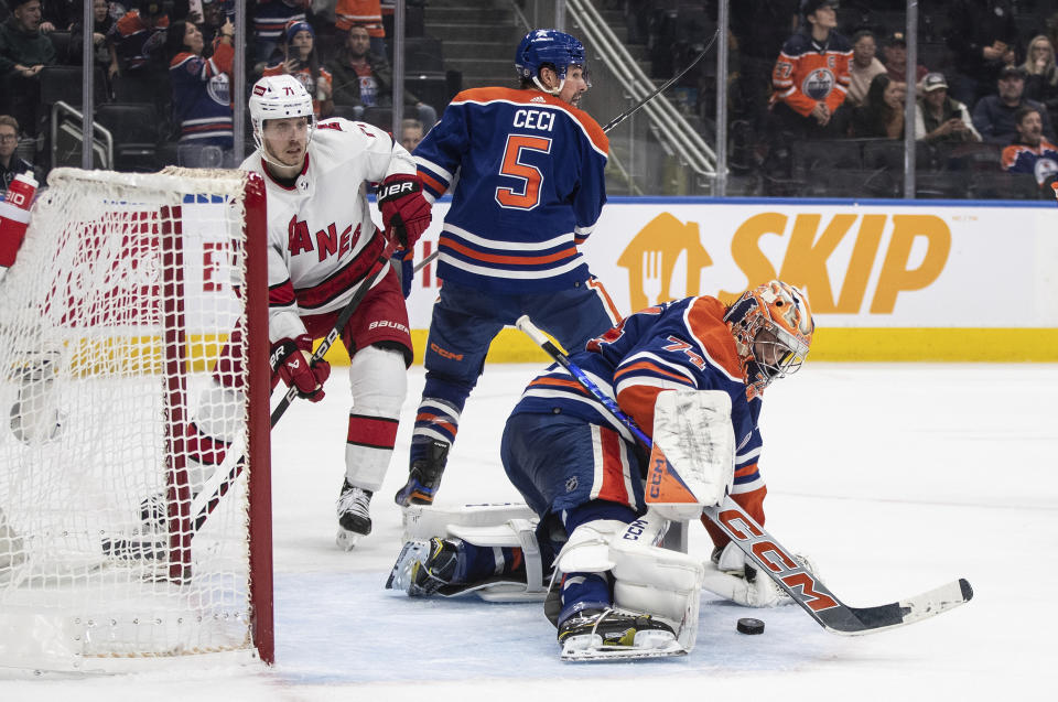 Carolina Hurricanes' Jesper Fast (71) and Edmonton Oilers' Cody Ceci (5) work near Oilers soalie Stuart Skinner (74), who makes a save during the third period of an NHL hockey game Wednesday, Dec. 6, 2023, in Edmonton, Alberta. (Jason Franson/The Canadian Press via AP