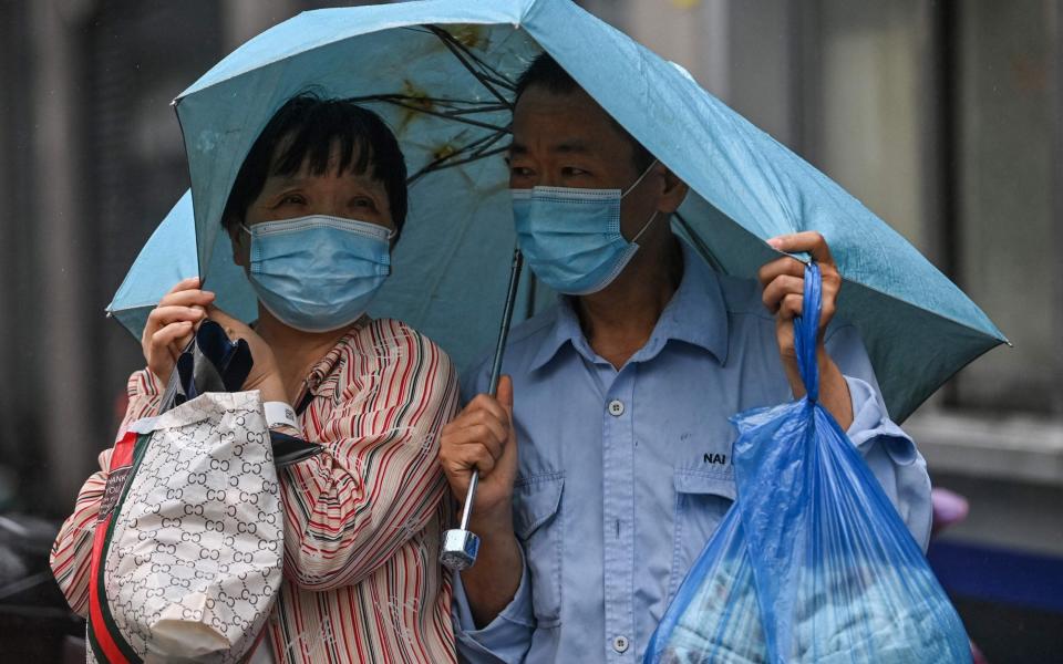  A couple shelters under an umbrella by amid inclement weather in Ningbo, eastern China's Zhejiang province - AFP