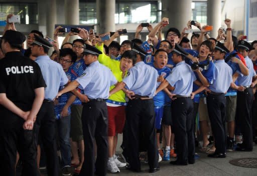 Police form a line in front of a cordon as Shanghai Shenhua fans shout to welcome former Chelsea football star Didier Drogba upon his arrival at Pudong international airport in Shanghai on July 14. Drogba was given a hero's welcome as he arrived in China to start a two-and-a-half year contract that is expected to make him one of football's highest-paid players