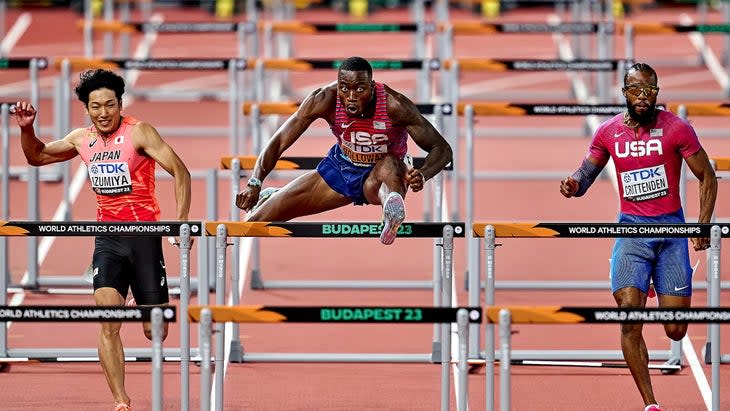 three men jump over hurdles 