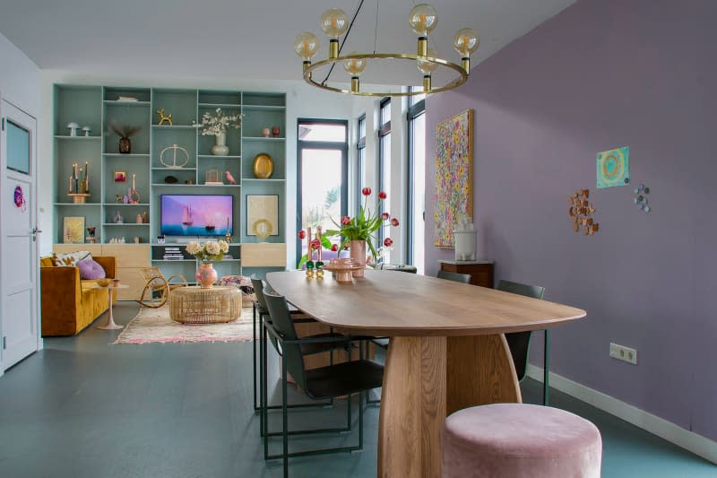 Wood table in pastel dining area and sky blue wall unit seen in living room.