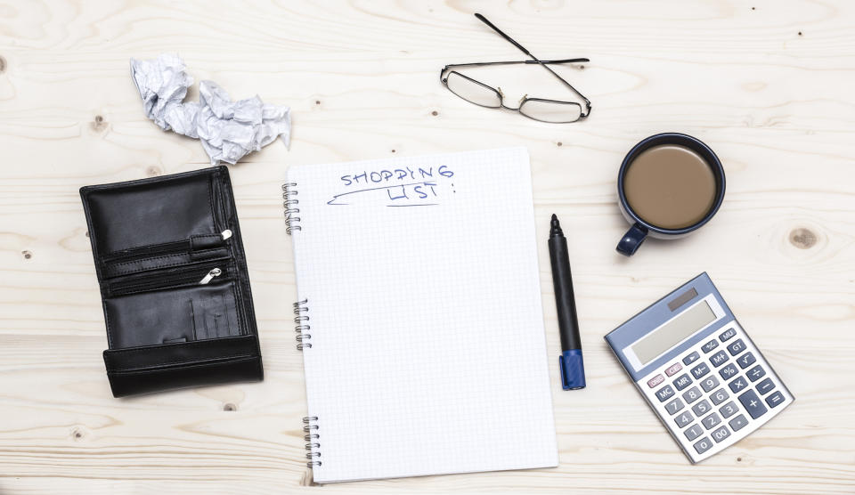 An notebook open to a page titled "shopping list" beside various desk items