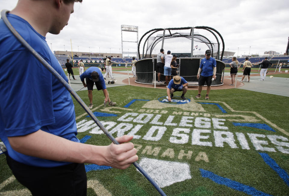 TD Ameritrade Park grounds crew paints the College World Series logo behind home plate during practice day for baseball's College World Series at TD Ameritrade Park, Friday, June 14, 2019, in Omaha, Neb. (Ryan Soderlin/Omaha World-Herald via AP)