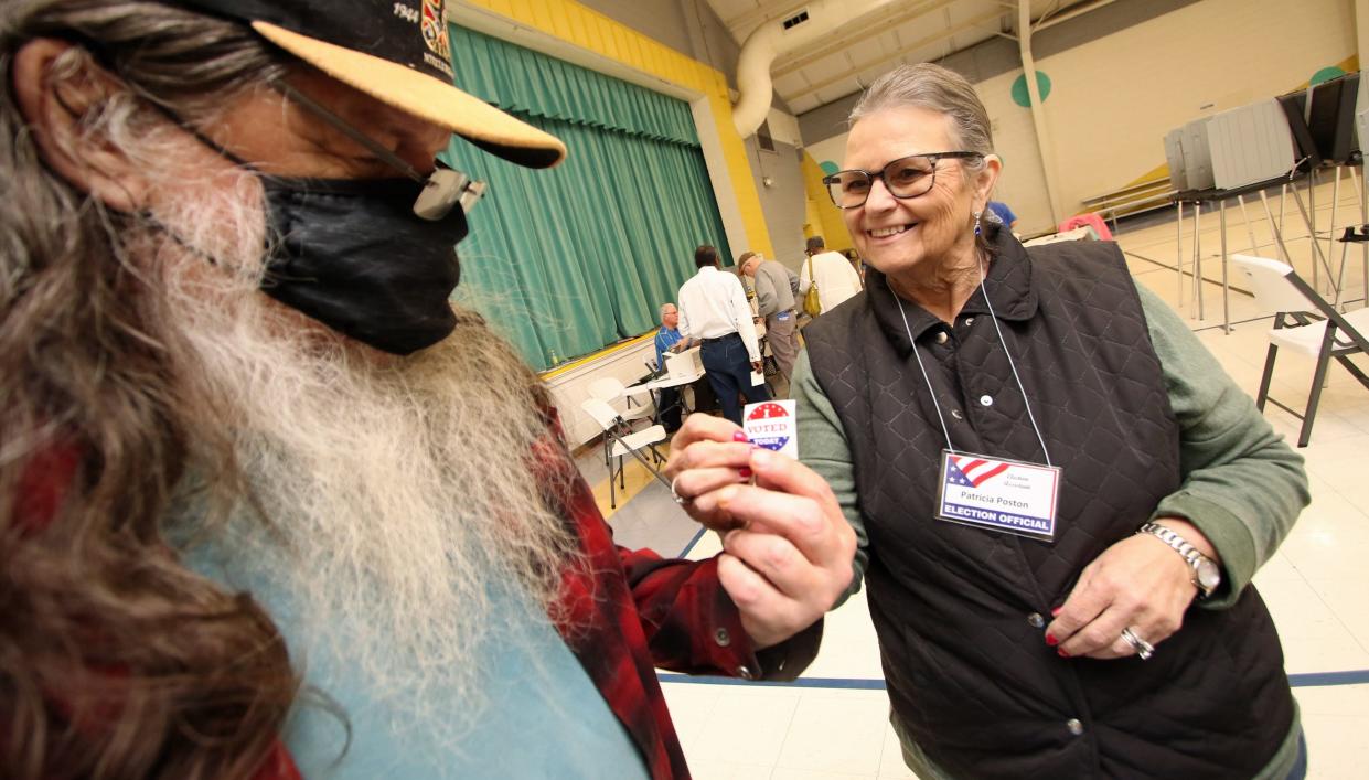 Patricia Poston hands out a sticker to Billy Davis after he voted at Holly Oak Park in the North Carolina primary Tuesday morning, March 5, 2024.