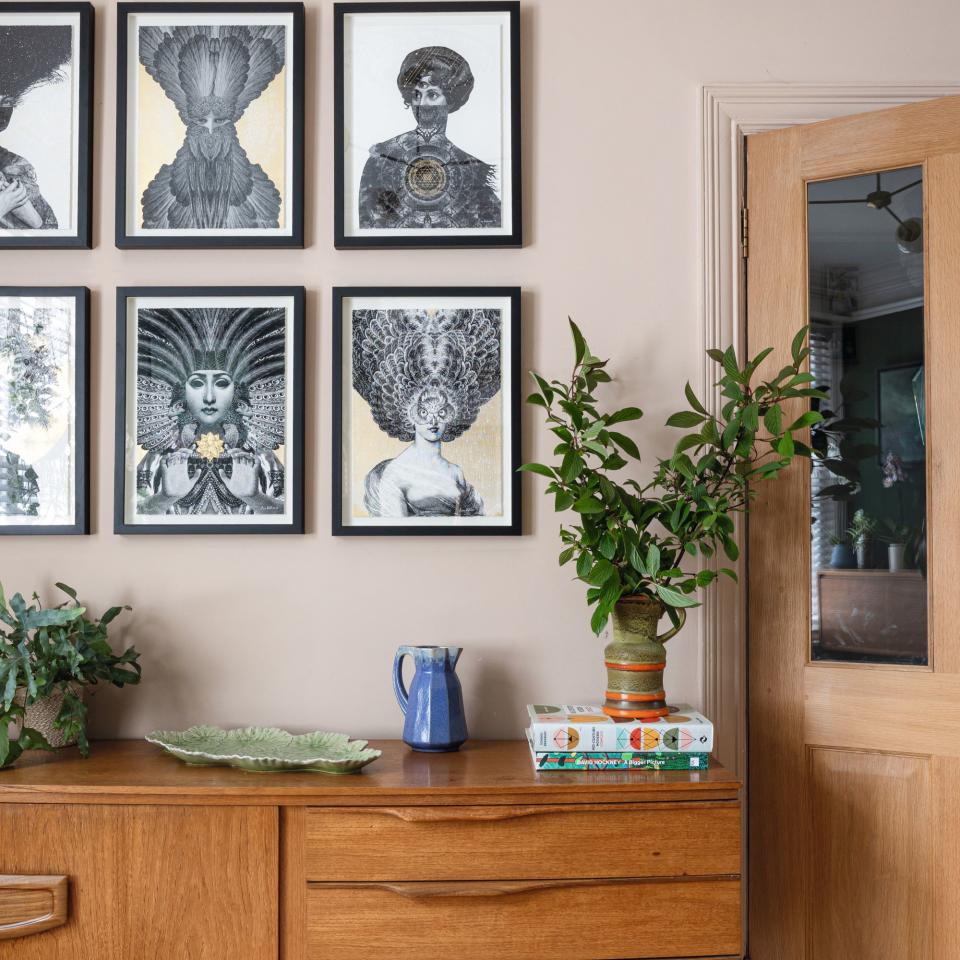 wooden console table underneath gallery of prints