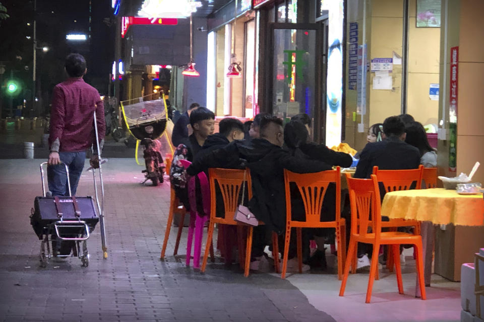 In this Dec. 6, 2019, photo, Wu Yi, who has struggled with Oxycontin abuse, wheels his portable amplifier past customers at an all-night restaurant in Shenzhen in southern China's Guangdong Province. Officially, pain pill abuse is an American problem, not a Chinese one. But people in China have fallen into opioid abuse the same way many Americans did, through a doctor's prescription. And despite China's strict regulations, online trafficking networks, which facilitated the spread of opioids in the U.S., also exist in China. (AP Photo/Mark Schiefelbein)