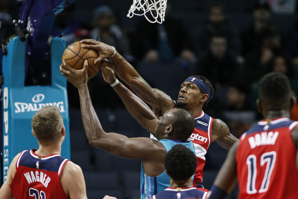 Washington Wizards guard Bradley Beal blocks a shot by Charlotte Hornets center Bismack Biyombo, center, in the first half of an NBA basketball game in Charlotte, N.C., Tuesday, Dec. 10, 2019. (AP Photo/Nell Redmond)