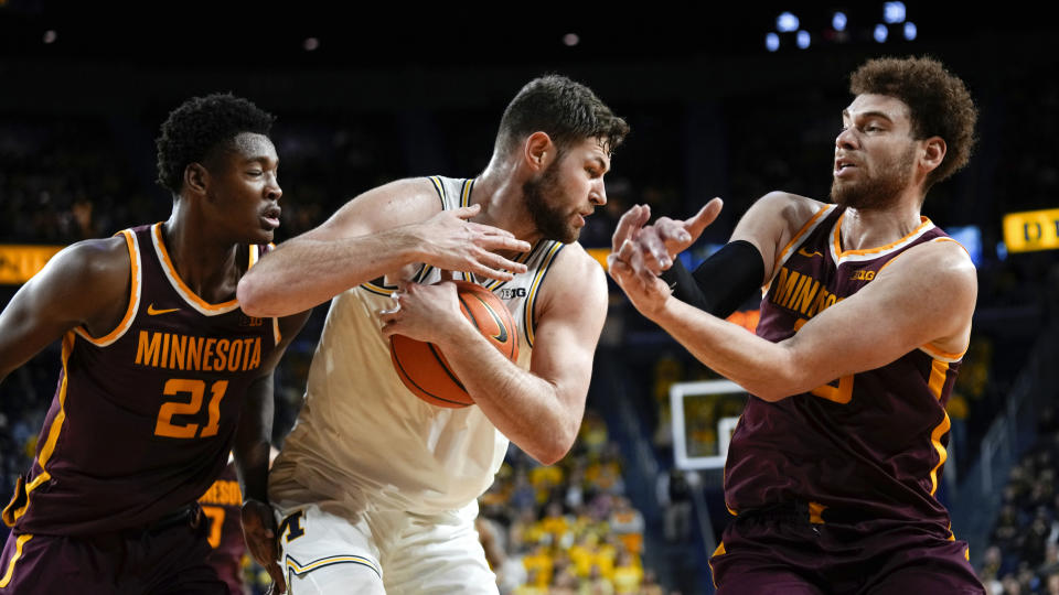 Michigan center Hunter Dickinson (1) pulls down a rebound from Minnesota forward Pharrel Payne (21) and Jamison Battle (10) in the second half of an NCAA college basketball game in Ann Arbor, Mich., Sunday, Jan. 22, 2023. (AP Photo/Paul Sancya)