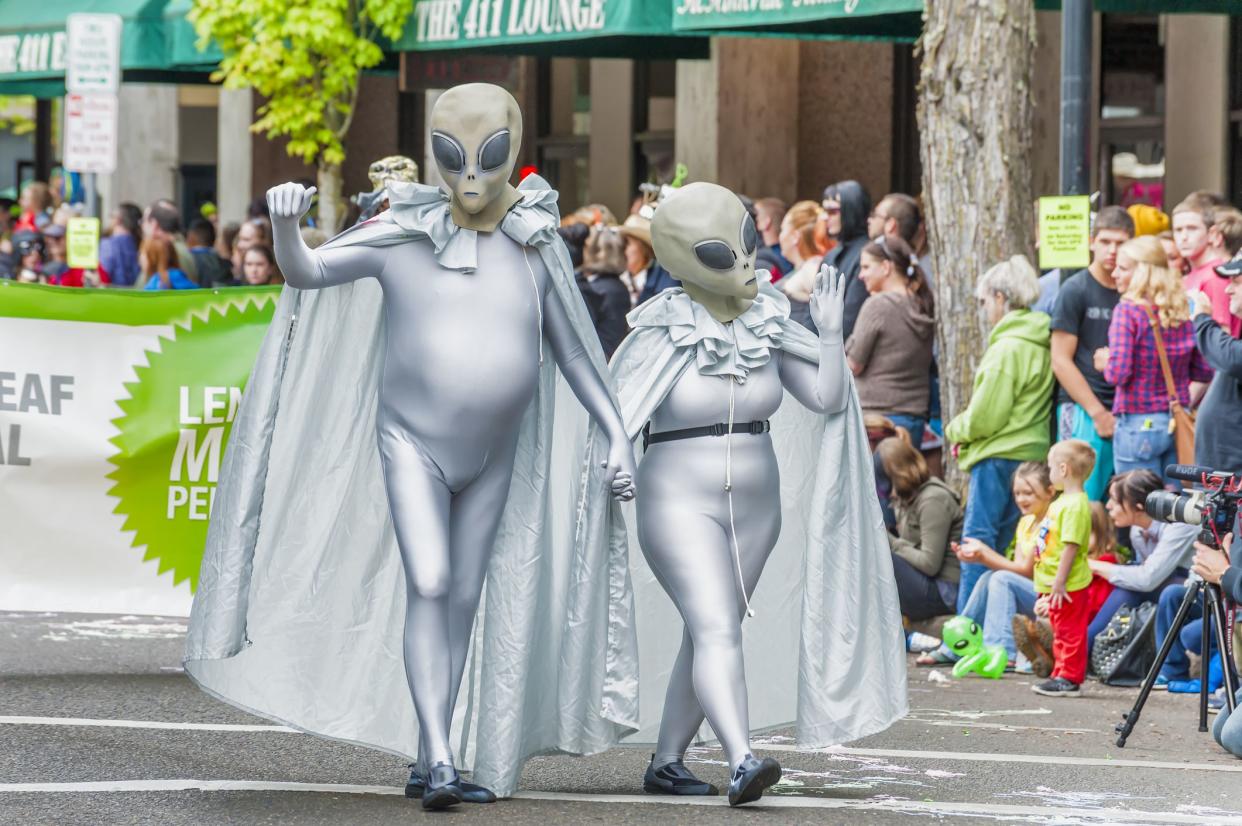 McMinnville, Oregon,USA - May 16, 2015: A couple wearing silver alien costumes walk down McMinnville Oregon's mainstreet in the parade of the annual UFO Festival.