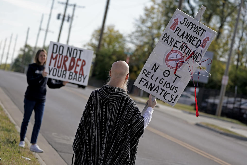 Demonstrators from both sides of the abortion issue stand outside a Planned Parenthood clinic Saturday, Oct. 15, 2022, in Kansas City, Kan. (AP Photo/Charlie Riedel)