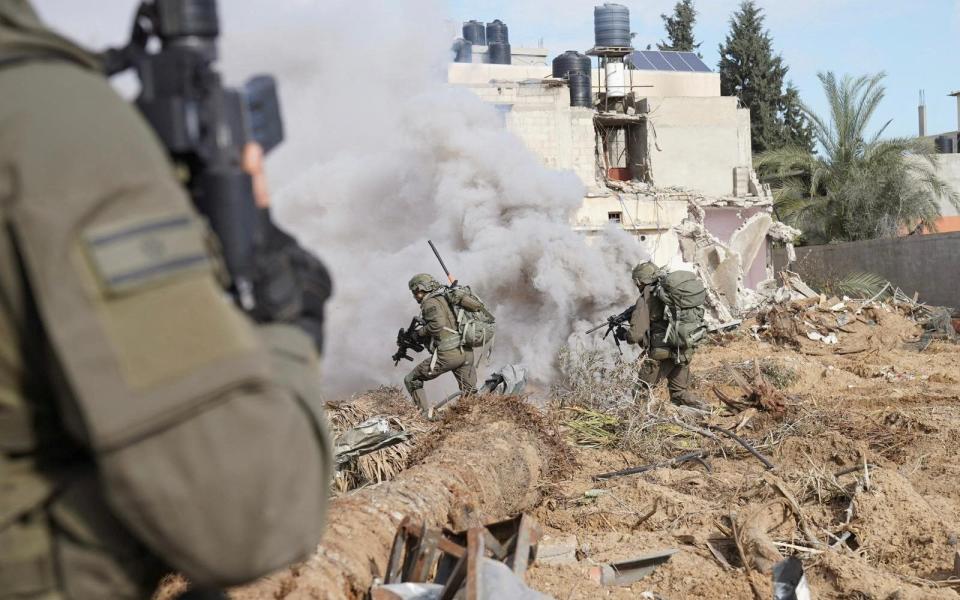 Israeli soldiers operate in Gaza as smoke billows in the background