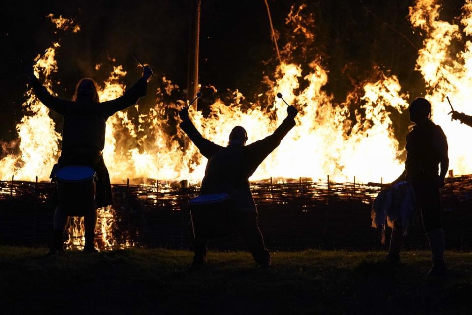 Pentacle Drummers play in front of a burning ceremonial Viking long boat at Butser Ancient Farm in Hampshire, to mark the autumn equinox (PA)