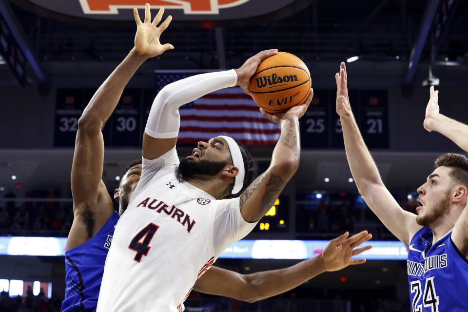 Auburn forward Johni Broome (4) shoots as Saint Louis forward Francis Okoro, left, and guard Gibson Jimerson (24) try to block the shot during the second half of an NCAA college basketball game Sunday, Nov. 27, 2022, in Auburn, Ala. (AP Photo/Butch Dill)