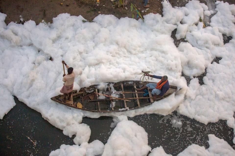 A man rows a boat in Yamuna River, covered by a chemical foam caused by industrial and domestic pollution, in Delhi. (AP)