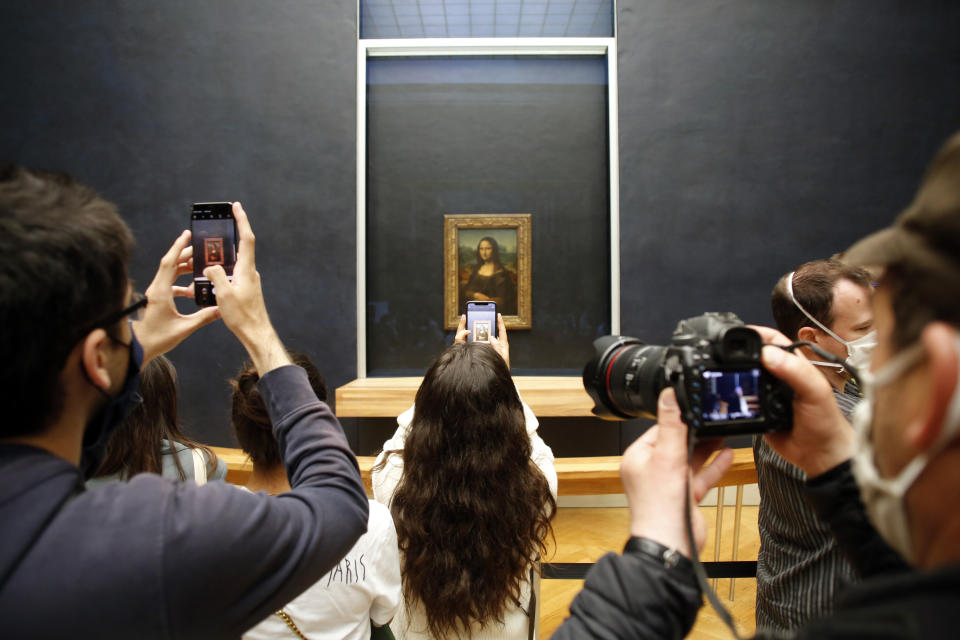 Visitors take photos of the Leonardo da Vinci's painting Mona Lisa, in Paris, Monday, July 6, 2020. The home of the world's most famous portrait, the Louvre Museum in Paris, reopened Monday after a four-month coronavirus lockdown. (AP Photo/ Thibault Camus)