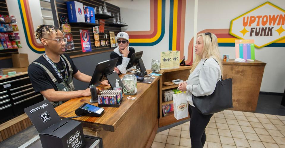 Uptown Funk sales manager Johnny Washington III, from left, and budtender Jason Deitenbeck talk with customer Sunny Holliday of Jackson at the Jackson dispensary Thursday. It’s been more than a year since the first legal sale of medical marijuana in the state.