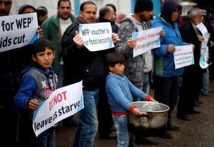 Palestinians hold signs during a protest against aid cut, outside United Nations' offices in Gaza City January 17, 2018. REUTERS/Suhaib Salem