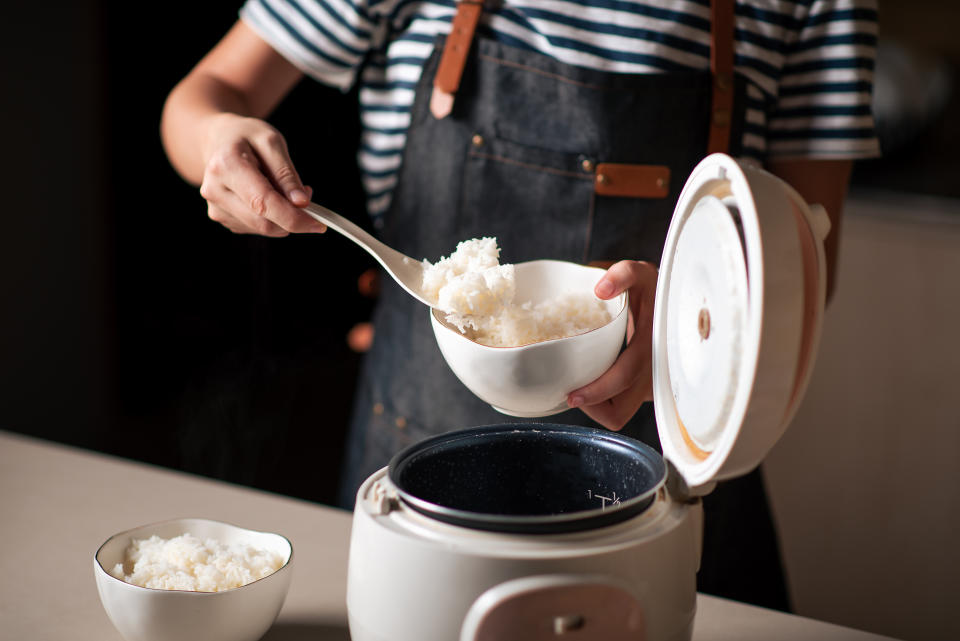 person scooping cooked rice out of their rice cooker