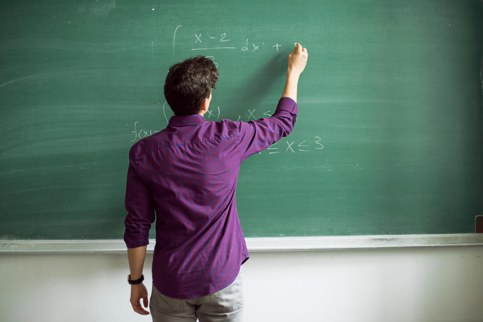 A teacher writing on a chalk board