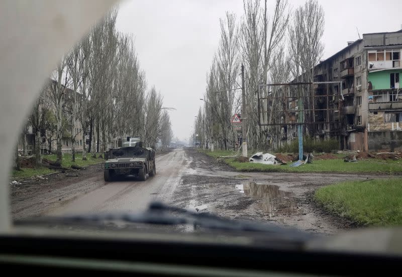 FILE PHOTO: A Ukrainian service member rides a military vehicle near residential buildings damaged by a Russian military strike in the front line town of Bakhmut