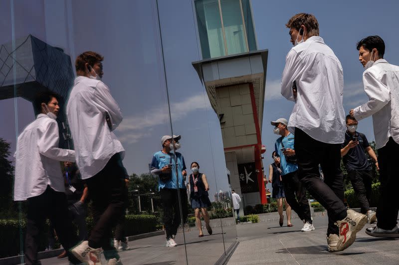 People look into a window of a shop, outside a mall in Beijing