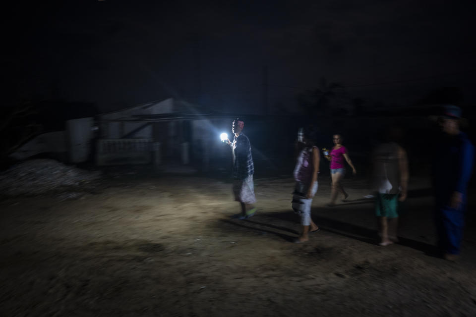 Residents walk along a street left dark one week prior by Hurricane Ian in La Coloma, Pinar del Rio province, Cuba, Wednesday, Oct. 5, 2022. (AP Photo/Ramon Espinosa)