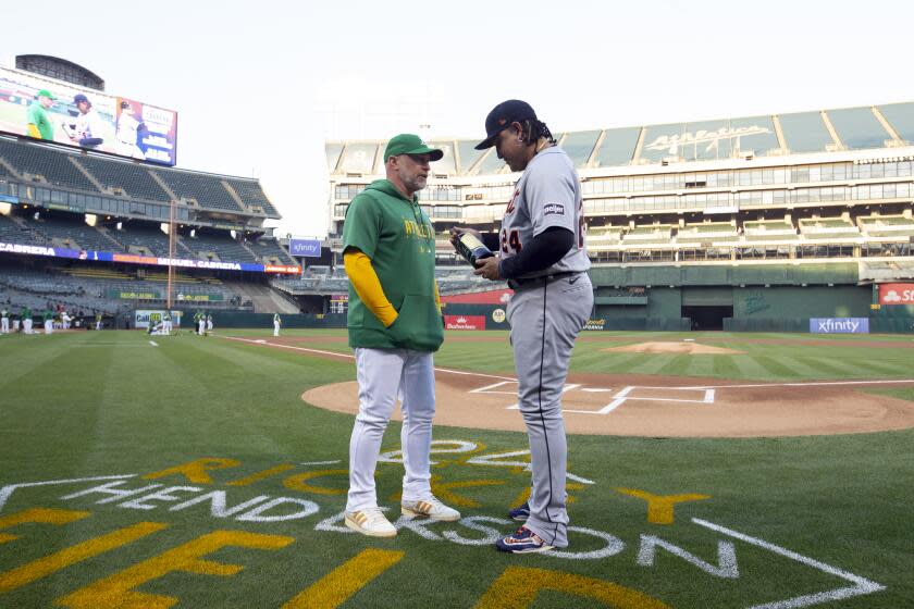Oakland Athletics manager Mark Kotsay presents a bottle of wine to Detroit Tigers designated hitter Miguel Cabrera