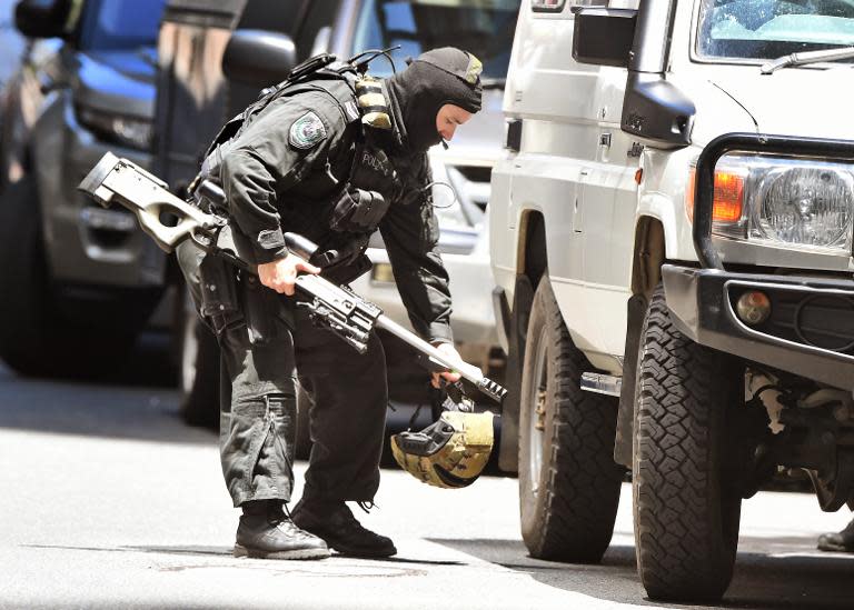 A police sniper walks to his vehicle during a hostage siege in the central business district of Sydney on December 15, 2014