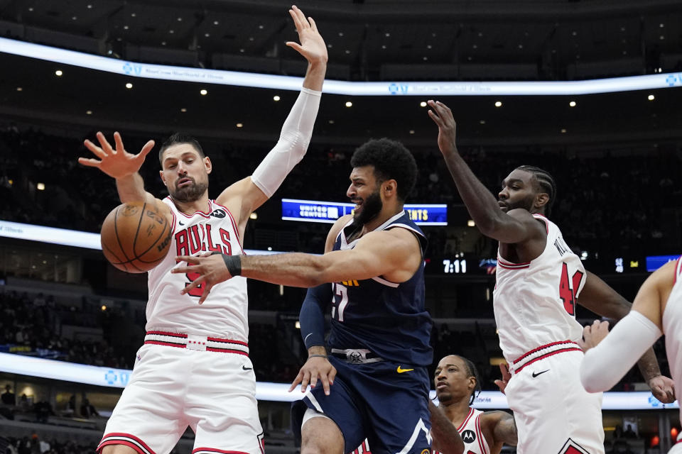 Denver Nuggets guard Jamal Murray, center, passes the ball as Chicago Bulls center Nikola Vucevic, left, and forward Patrick Williams defend during the first half of an NBA preseason basketball game in Chicago, Thursday, Oct. 12, 2023. (AP Photo/Nam Y. Huh)