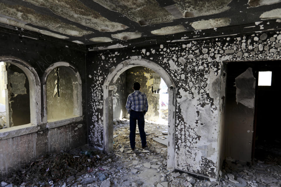 A former policeman walks through an abandoned home, torched by the Zetas cartel eight years back, in Allende, Coahuila state, Mexico, Tuesday, Dec. 3, 2019. In an act of revenge cartel members in 2011 razed and burned houses and disappeared people just by bearing the last name of the alleged traitor. Residents of the small town of Villa Union, 12 miles from Allende, said Tuesday that they fear a return to the days of 2010-2013, when the old Zetas cartel killed, burned and abducted Coahuila citizens. (AP Photo/Eduardo Verdugo)