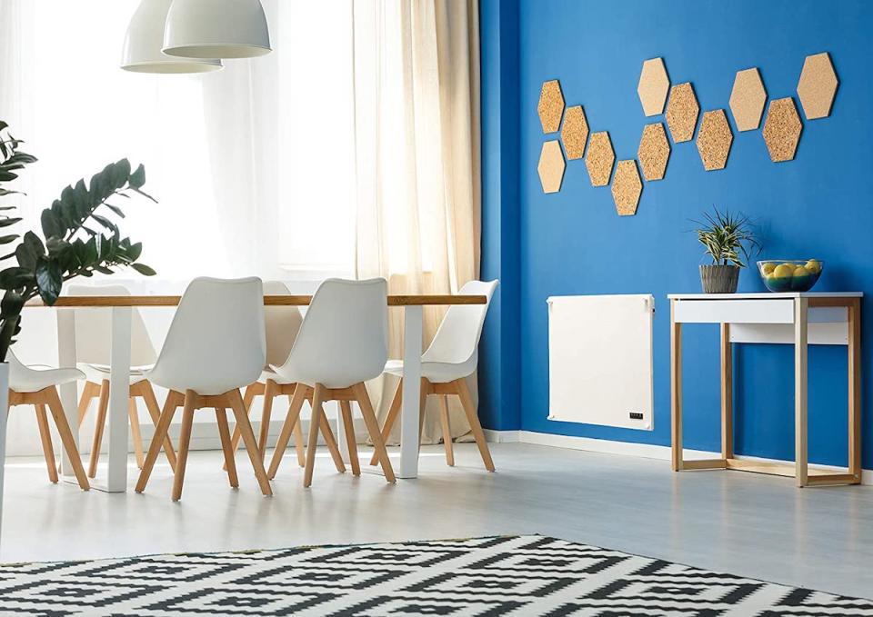 Modern dining table and chairs, black and white rug, with bright blue accent wall with a radiant wall heater.