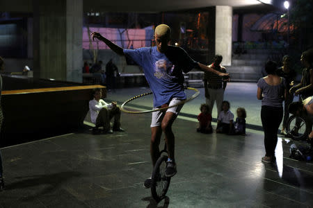 A youth practices on a unicycle while hula hooping at the Teresa Carreno theatre area where friends meet to practice in Caracas, Venezuela, March 22, 2019. REUTERS/Ivan Alvarado