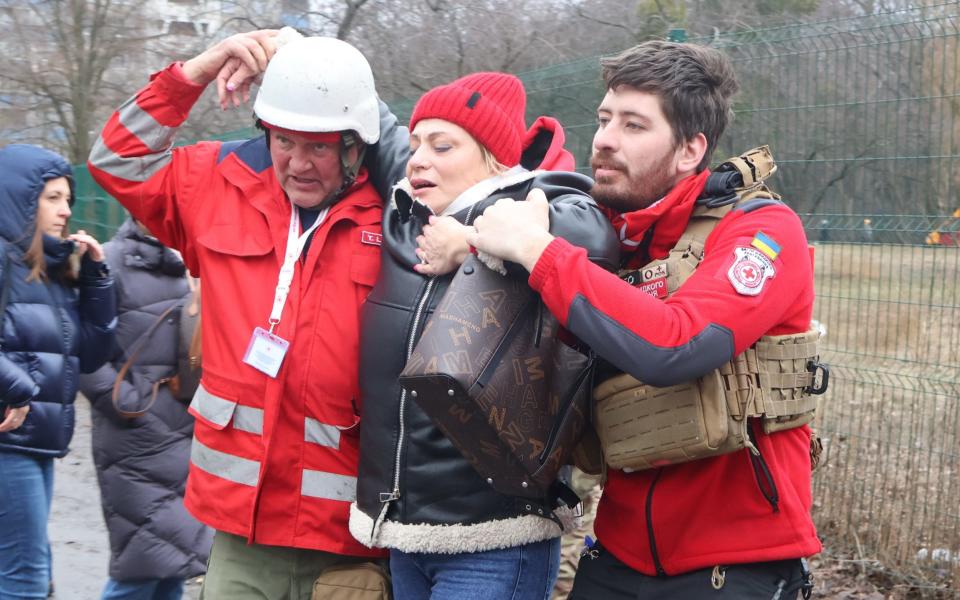 Rescuers help a woman in Kyiv after a Russian missile attack