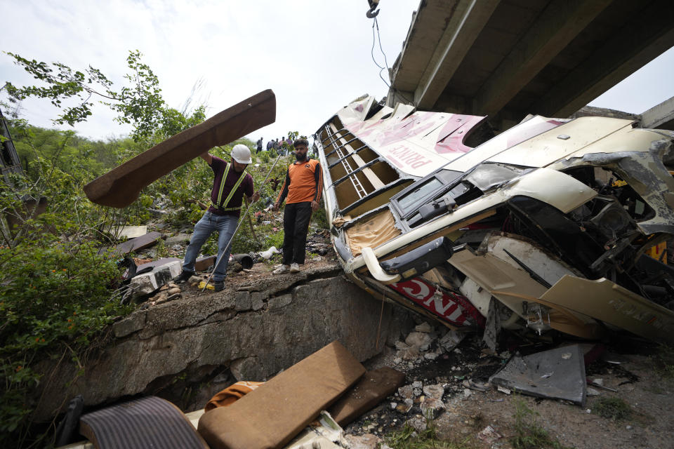 Jammu & Kashmir State Disaster Response Force (SDRF) personnel inspect the wreckage after a bus carrying Hindu pilgrims to a shrine skid off a highway bridge into a Himalayan gorge near Jammu, India, Tuesday, May 30, 2023. (AP Photo/Channi Anand)