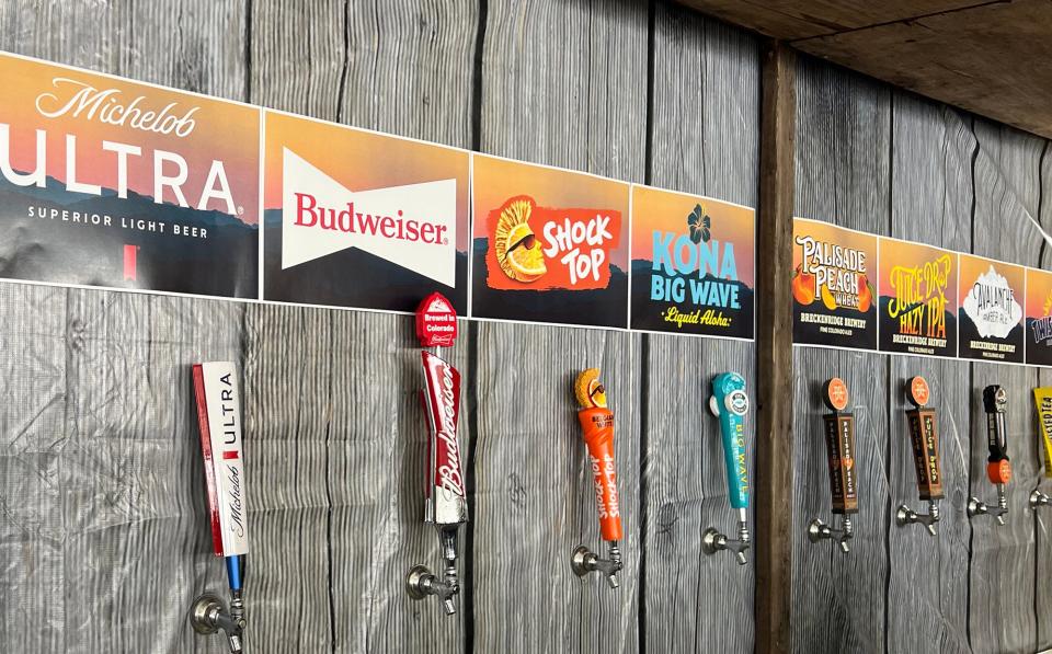 beer taps beneath their respective brand's labels on a wood plank wall