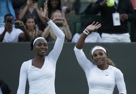 Venus Williams of the U.S. (L) and Serena Williams of the U.S.wave after defeating Oksana Kalashnikova of Georgia and Olga Savchuk of Ukraine in their women's doubles tennis match at the Wimbledon Tennis Championships, in London June 25, 2014. REUTERS/Max Rossi